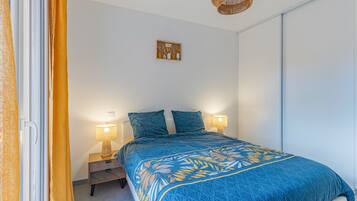 Ein Schlafzimmer mit einem Bett, zwei Nachttischlampen, einem Nachttisch, einer Wandablage mit Dekoration und einer Deckenleuchte.