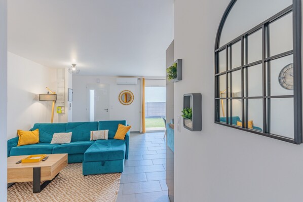 A modern living room with a teal sofa, a wooden coffee table, and a patterned rug.