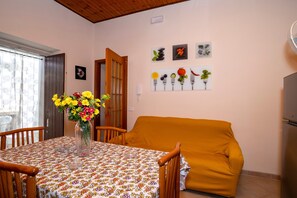 Un comedor con una mesa dispuesta para dos personas, un sofá y una pared decorada con cuadros.