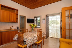 Una cocina con armarios de madera, una mesa de comedor con sillas, un televisor y una ventana con vistas.