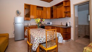 Une cuisine de taille réduite, dotée de meubles en bois, d’un réfrigérateur, d’un four à micro-ondes et d’une table à manger avec des chaises.