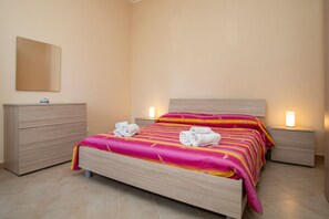Una cama bien hecha con un edredón a rayas, dos mesitas de noche con lámparas y un aparador de madera.