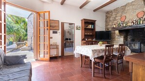 An open-plan living area with a dining table, chairs, a sofa, a fireplace, and a television.