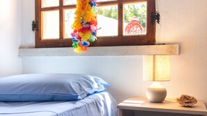 A bed with blue bedding, a bedside lamp, and a colorful hanging decoration.