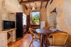 A rustic dining area with a wooden table, wicker chairs, a television, and a fireplace.