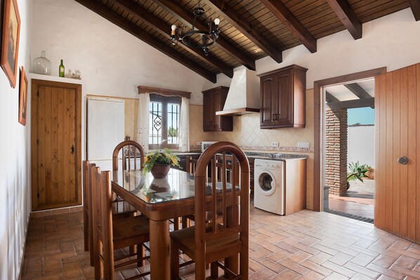 A kitchen with wooden cabinets, a washing machine, and a dining table with chairs.