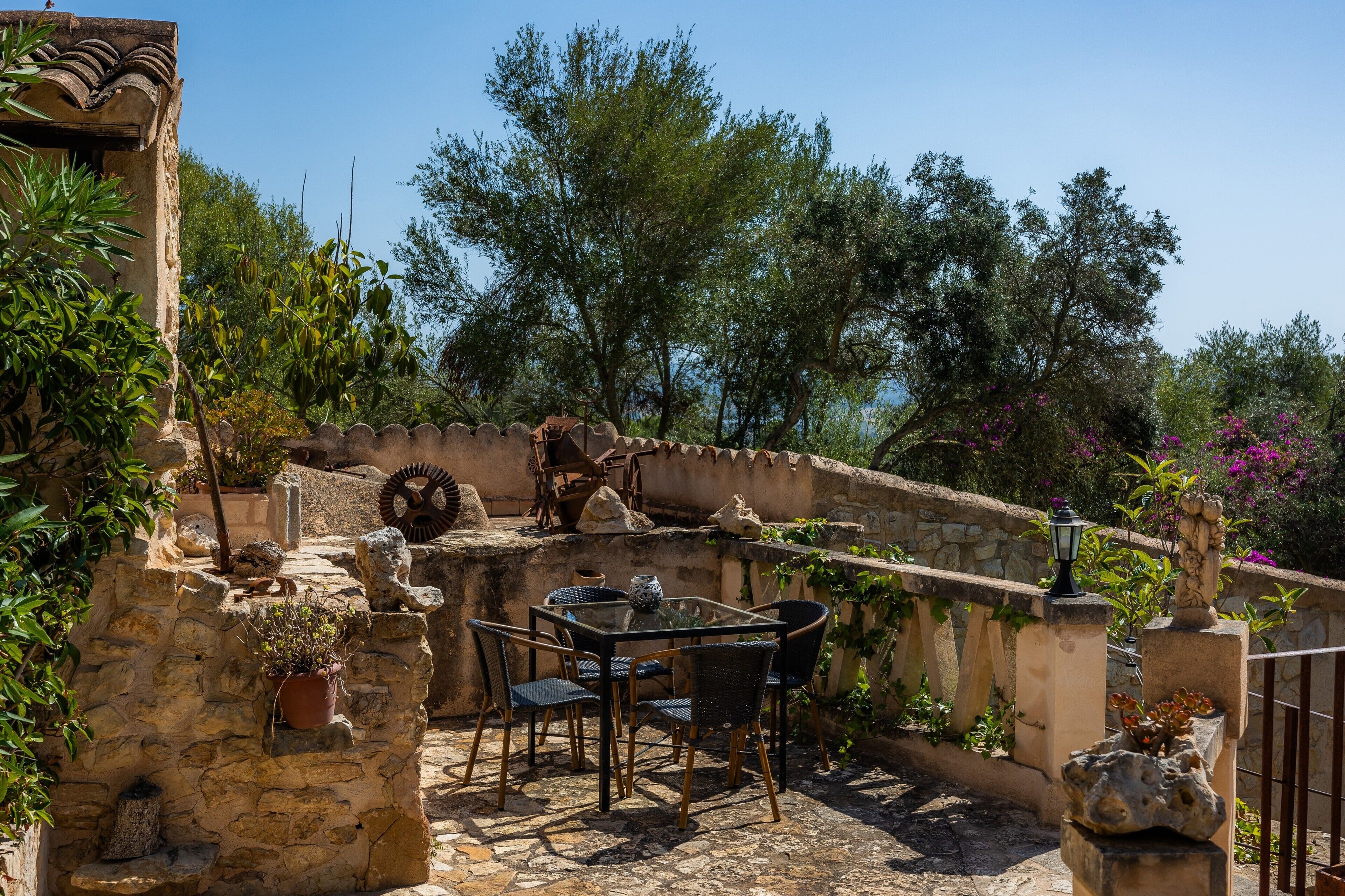 Un patio al aire libre con paredes de piedra, una mesa con sillas y macetas con plantas.