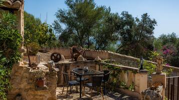 Un patio al aire libre con paredes de piedra, una mesa con sillas y macetas con plantas.