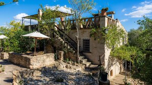 Un espace extérieur doté d’un escalier en pierre, d’une pergola en bois et d’un bâtiment rustique avec une fenêtre et une porte.
