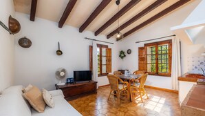 Une pièce comprenant un canapé, une table à manger, des chaises, un téléviseur et un ventilateur.