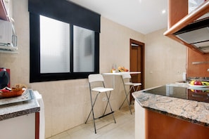 A kitchen with a window, a white countertop, a sink, and a stove.