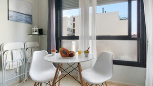 A room with a round table, two white chairs, a fruit bowl, a glass pitcher, and a white lantern on a shelf. - Vacation Home "Laura y Juan" with Sea View & Wi-Fi (Las Palmas de Gran canaria)