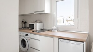 A modern kitchen with white cabinetry, a microwave, a washing machine, and a dishwasher.