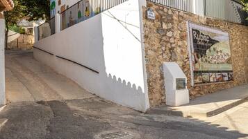 Un edificio blanco con fachada de piedra, una escalera que conduce a una entrada con reja, y un mural de azulejos que anuncia un restaurante.