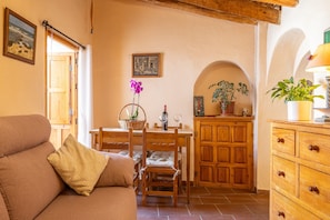 A cozy living room with a sofa, wooden dining table, chairs, and a cabinet. - Holiday Home "Zarzamora De Rubite" with Sea Views, Private Terrace and Wi-Fi (Rubite)
