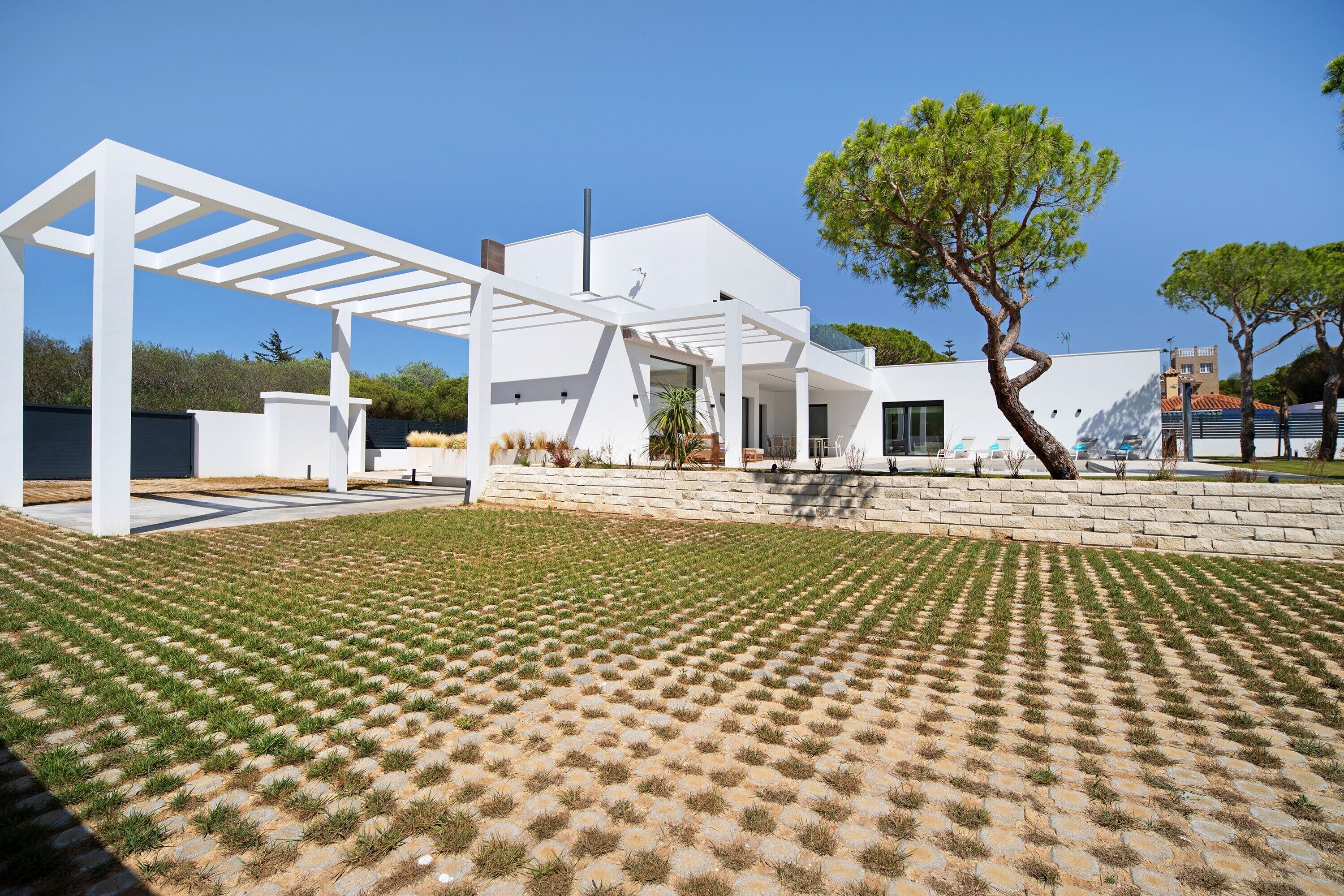 Een modern huis met een witte gevel, een overdekt terras en een verzorgd gazon.