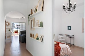 Un intérieur moderne avec un couloir menant à un espace repas, un bureau avec une chaise et un lit avec une couverture.