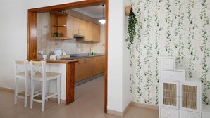 Una cocina con armarios de madera, una encimera y dos sillas blancas.