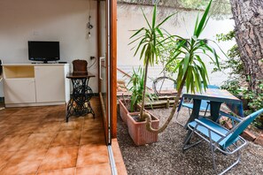 Une pièce comprenant une télévision, une machine à coudre, une petite table, une chaise et des plantes en pot.
