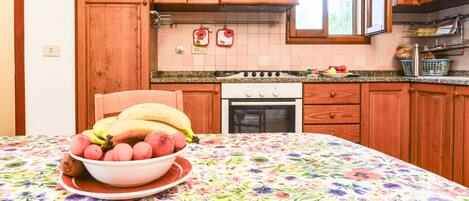 A kitchen with wooden cabinets, a stove, and a table with a floral tablecloth.