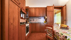 A kitchen with wooden cabinets, a stove, and a dining area with a table and chairs.