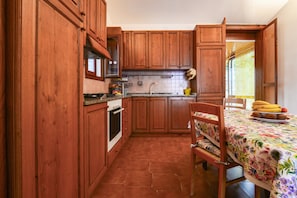 Una cocina con armarios de madera, una estufa y un comedor con mesa y sillas.
