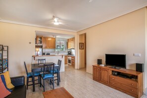 A compact living space with a dining area, kitchenette, and a TV on a wooden cabinet.