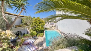 A poolside area with a clear view of the pool, surrounded by lush greenery and a white building. - Villa 'Blu La Patronale' with Sea View, Shared Pool and Wi-Fi (Castro)