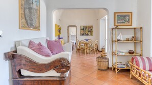 A living room with a sofa, a dining area with chairs, a bookshelf, and a painting on the wall. - Villa 'Blu La Patronale' with Sea View, Shared Pool and Wi-Fi (Castro)