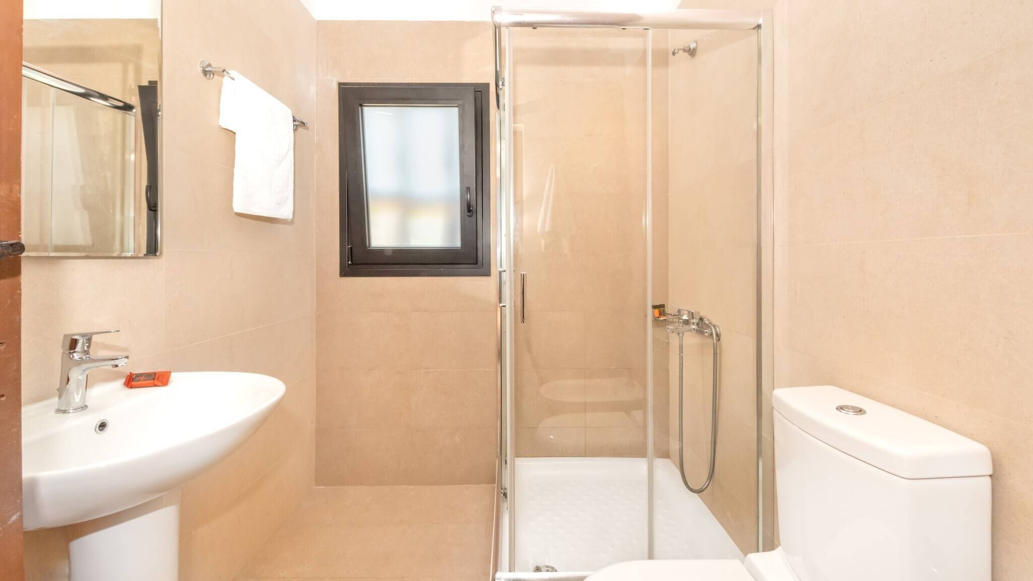 A bathroom with a glass-enclosed shower, a sink, and a toilet.