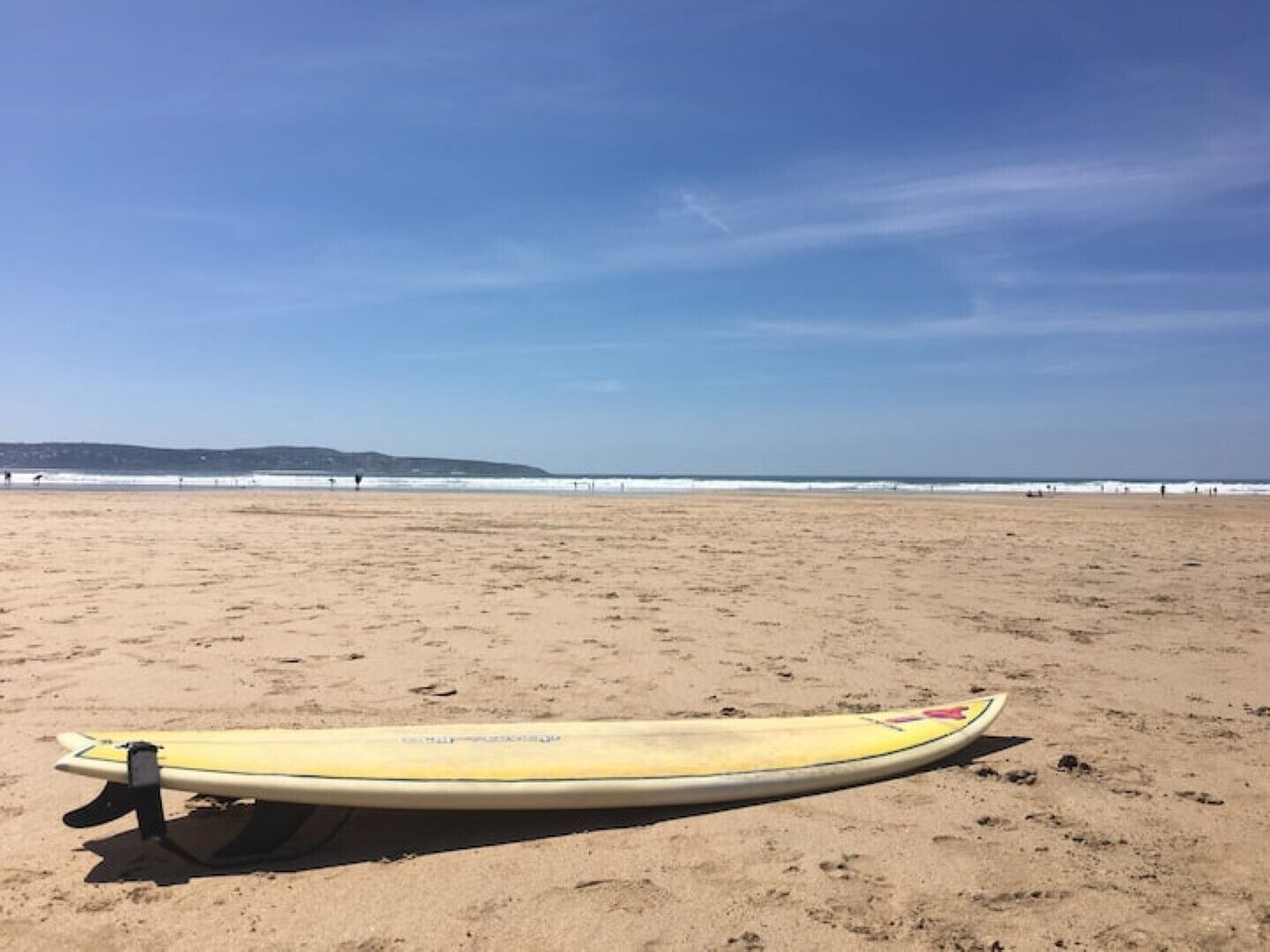 Una tabla de surf sobre una playa arenosa con cielo despejado.