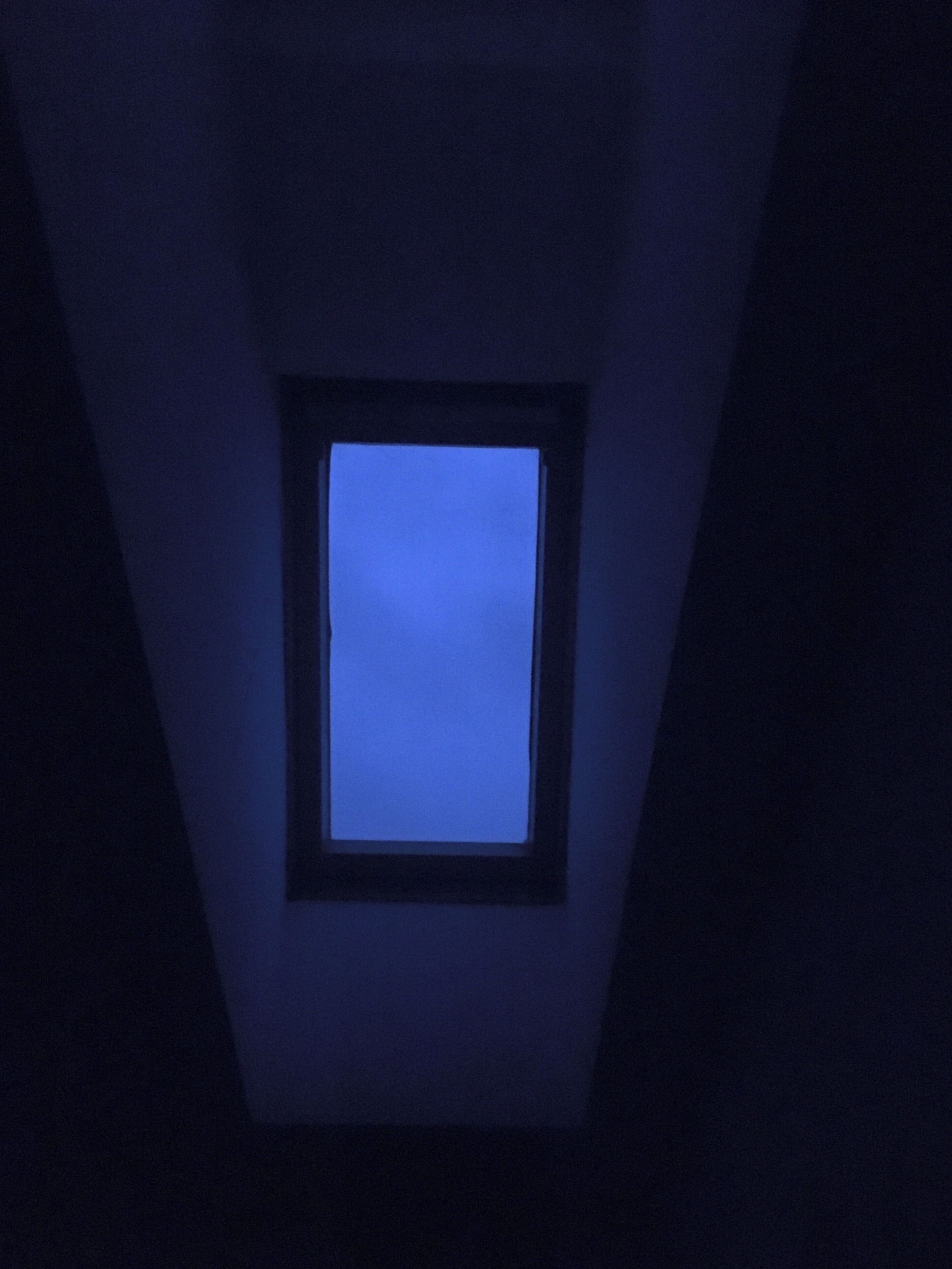 A dark room with a small, illuminated window.