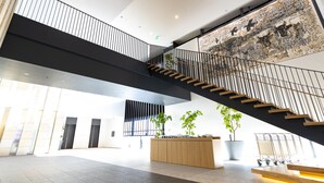 Un hall d’entrée spacieux, doté d’un escalier moderne, d’un comptoir de réception et de grandes fenêtres laissant entrer la lumière naturelle.
