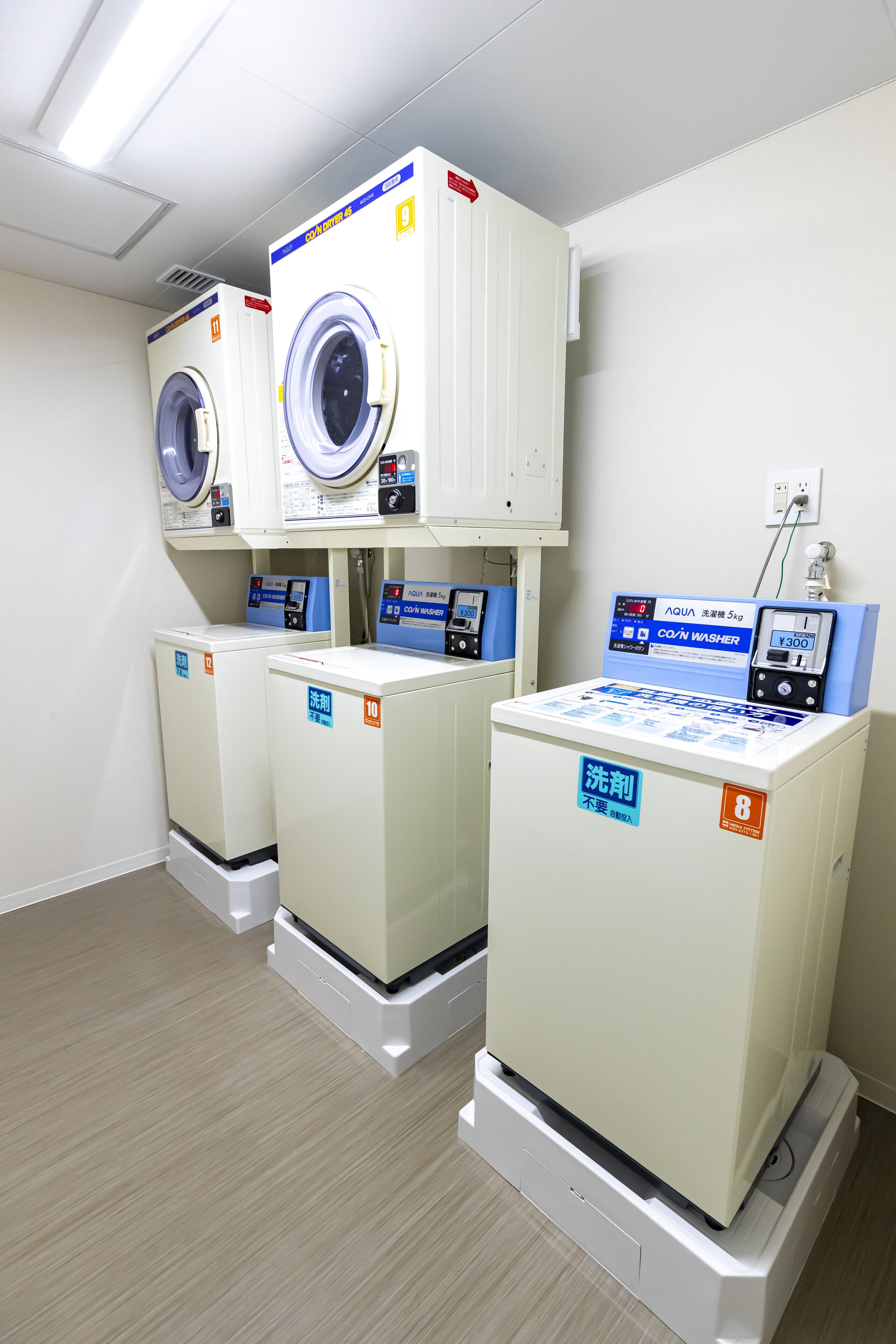 A laundry facility with three washing machines and a control panel.