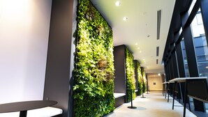 Un intérieur moderne avec un long couloir, des jardins verticaux et une rangée de tables et de chaises.