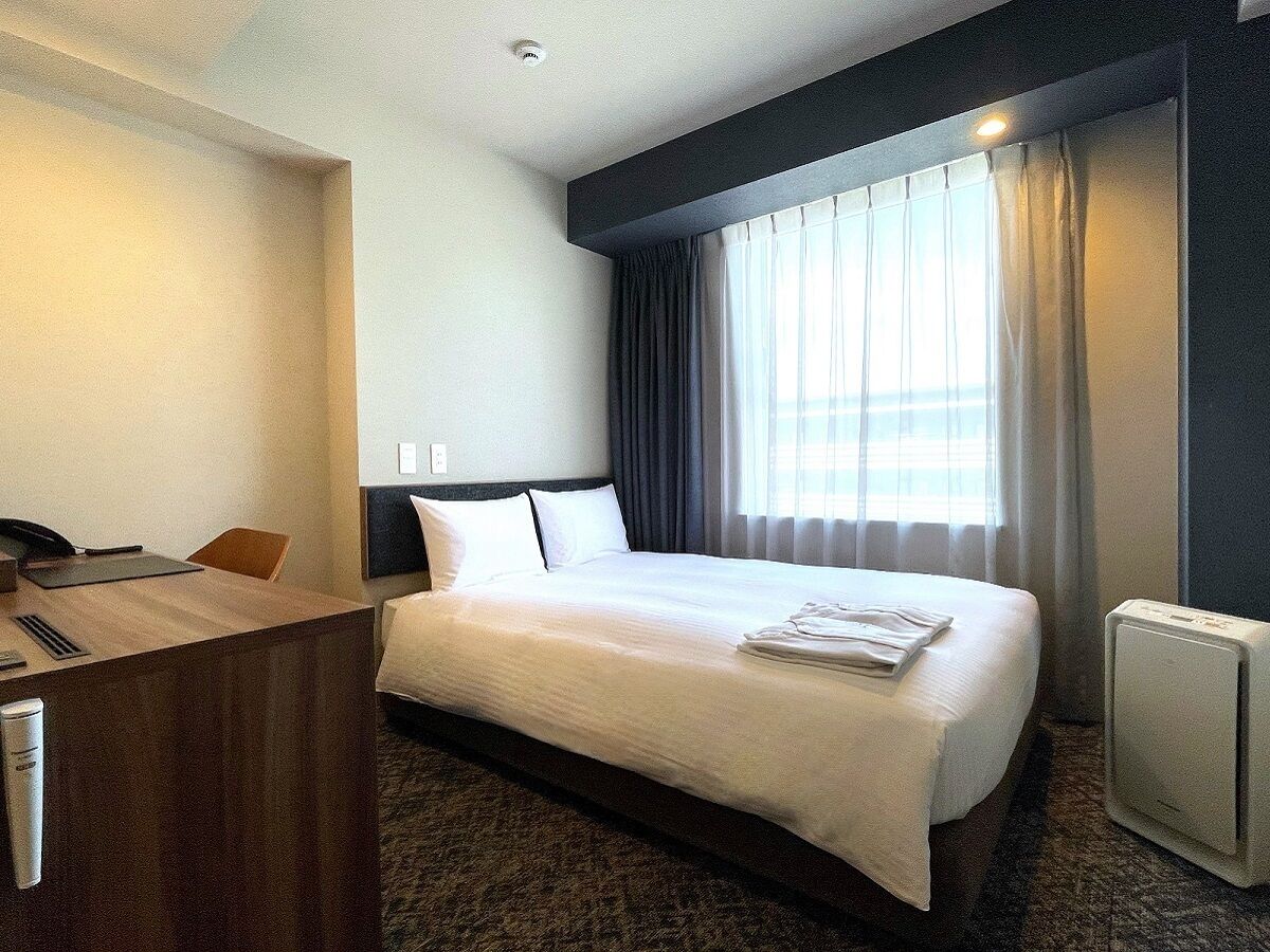 A hotel room with a bed, a desk, and a radiator.
