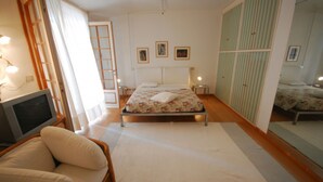 A bedroom with a bed, a chair, a TV, a wardrobe, and a ladder. - Seaside Villa With Private Garden (Lignano Sabbiadoro)