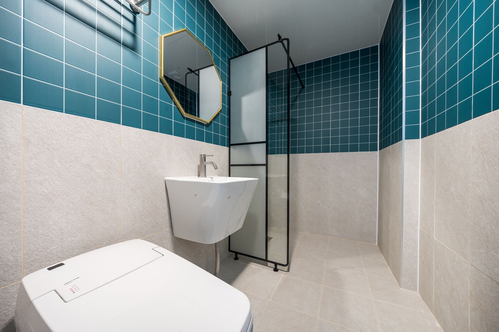 Une salle de bain avec un lavabo blanc, un miroir et un espace douche.