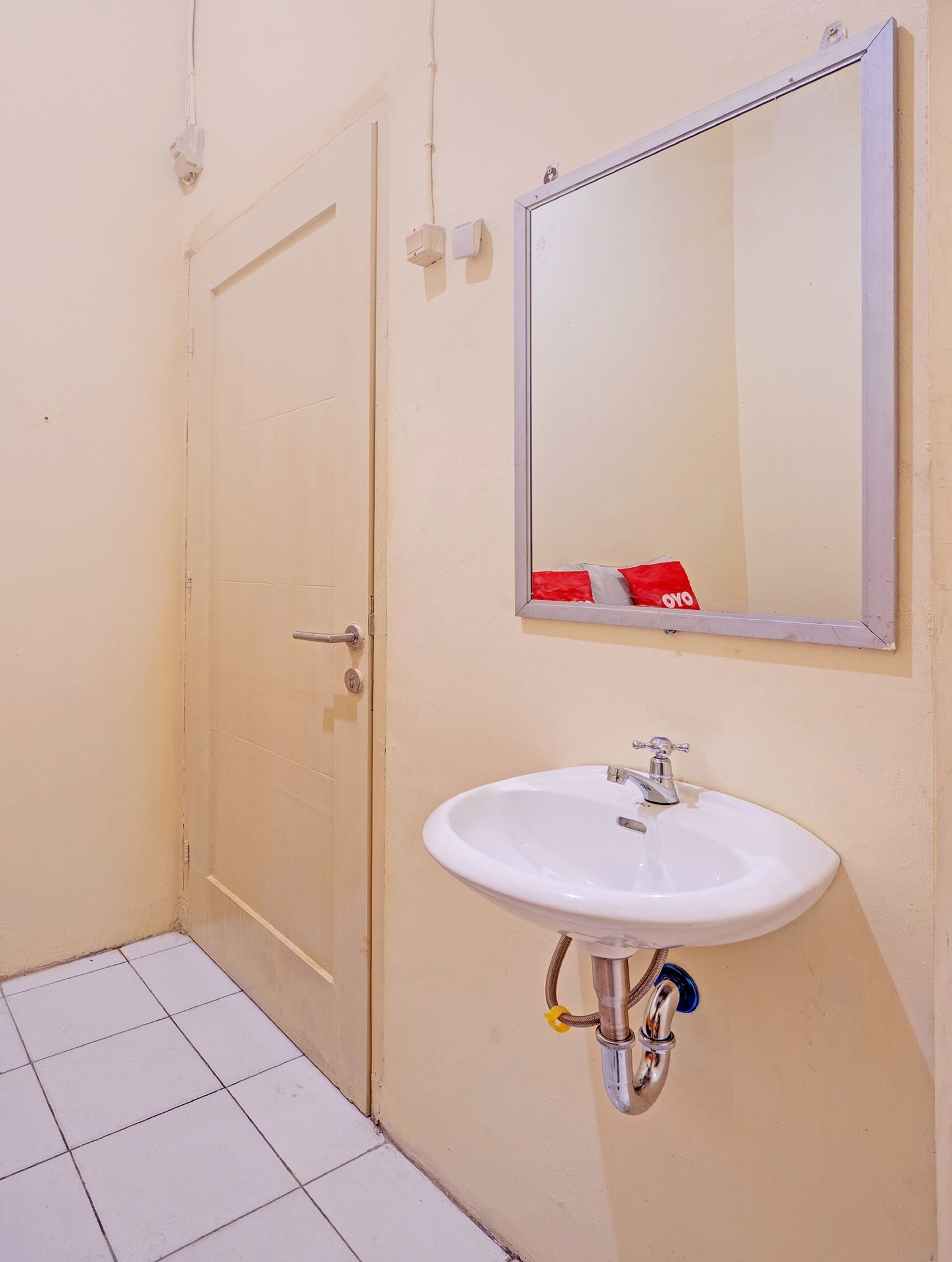 Une salle de bain avec un lavabo blanc, un miroir et une porte.