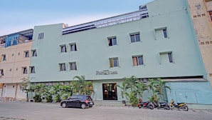 Un hôtel appelé «Pinnacle Hotel», avec une façade bleu clair, de nombreuses fenêtres et un espace de stationnement où sont garées plusieurs motos.