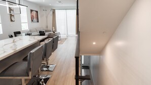 A modern hotel room with a long dining table, seating, and a large window with curtains. - MODERN 4BR TOWNHOME BUILT 2023 w/ 2-CAR GARAGE WITH EV CHARGER & 2 BALCONIES (p63) (Los Angeles)