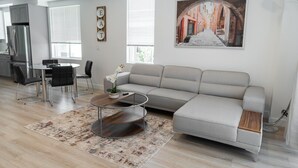 A modern living room with a sofa, coffee table, and dining area. - MODERN 4BR TOWNHOME BUILT 2023 w/ 2-CAR GARAGE WITH EV CHARGER & 2 BALCONIES (p63) (Los Angeles)