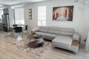A modern living room with a sofa, coffee table, and dining area.