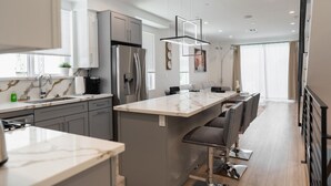 A modern kitchen with a central island, stainless steel appliances, and a bar area. - MODERN 4BR TOWNHOME BUILT 2023 w/ 2-CAR GARAGE WITH EV CHARGER & 2 BALCONIES (p63) (Los Angeles)