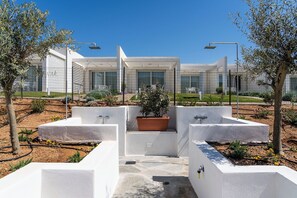 A modern outdoor area with a central planter, two water features, and a white building in the background.