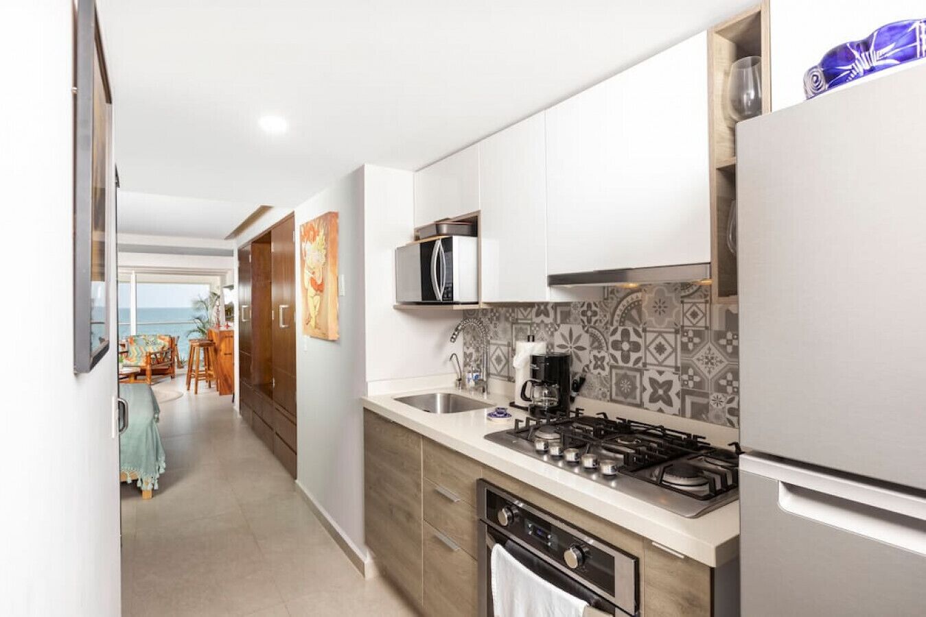 A modern kitchen with stainless steel appliances, a tiled backsplash, and a view to the dining area.
