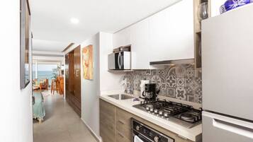 A modern kitchen with stainless steel appliances, a tiled backsplash, and a view to the dining area.