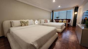 Habitación de hotel con dos camas, un escritorio y una ventana con persianas.
