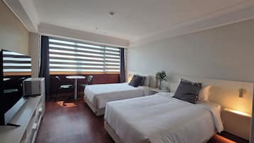 Ett hotellrum med två sängar, ett skrivbord, en stol och en tv.