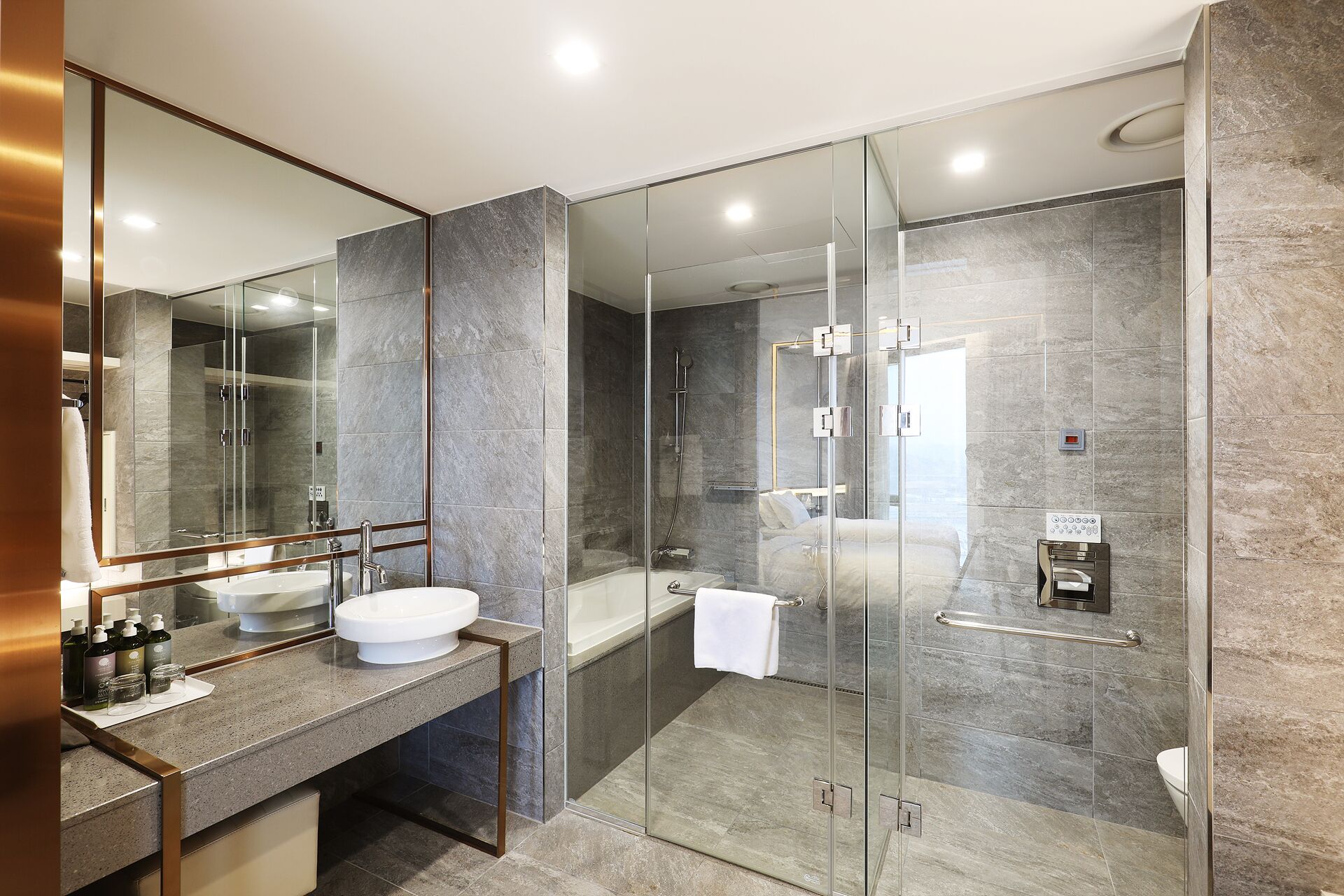 A modern bathroom with a glass-enclosed shower, a large mirror, and a vanity with a sink and countertop.